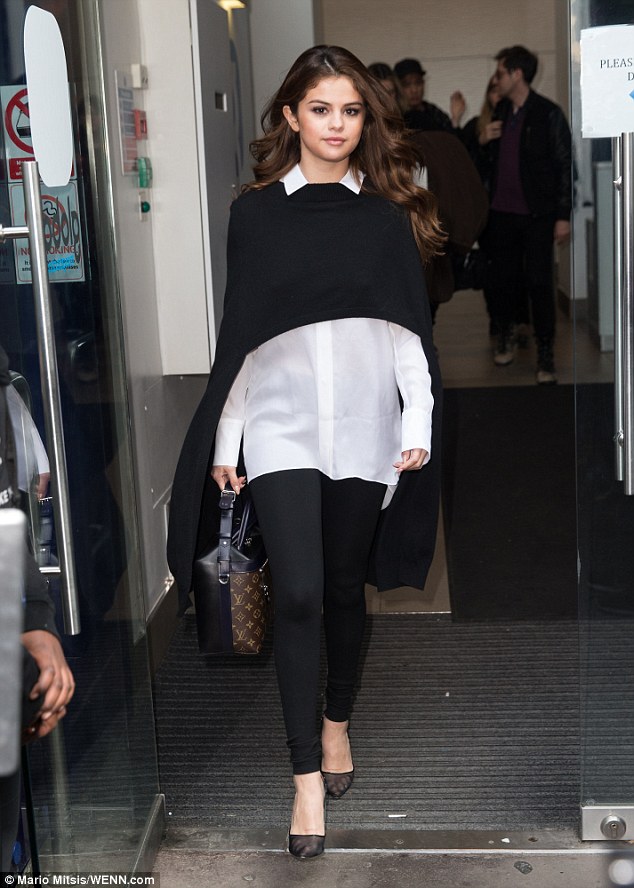 Monochrome magic: The brunette's fourth outfit of the day was more casual - a sheer white shirt, teamed with skintight black leggings and a black poncho