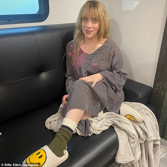 In between scenes: Billie also shared a photo from what appeared to be her trailer, as she lounged on a couch while wearing a grey dress, green socks and cozy slippers