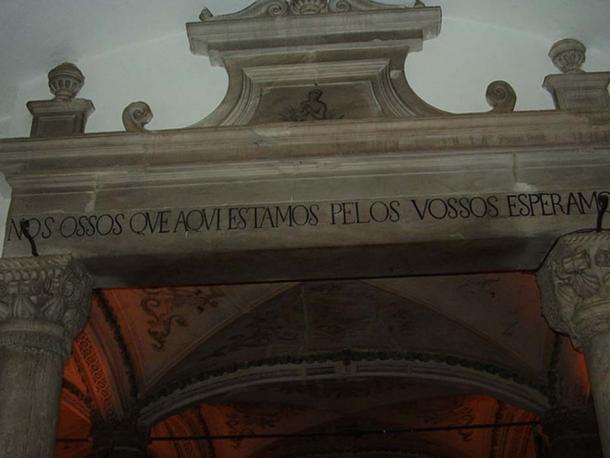 La inscripción sobre la puerta se traduce como, "Los huesos estamos aquí esperando el tuyo."