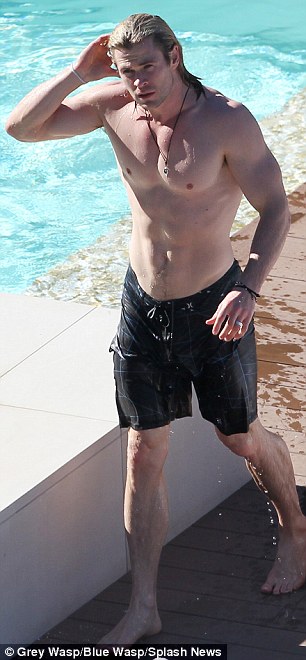 Dripping wet: The water glistened on Hemsworth's muscles as he exited from the pool, before covering up in a towel